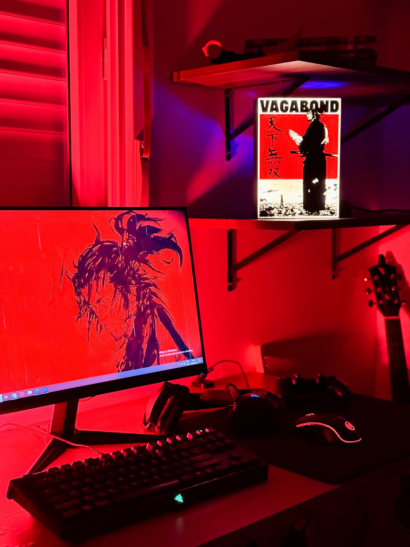 Luminária Vagabond acesa em estante acima de setup gamer com luz vermelha